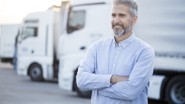 Transportunternehmer vor der eigenen Lkw-Reihe