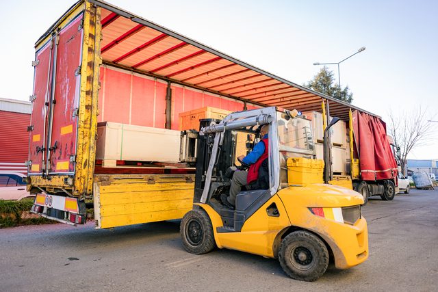 Gabelstapler belädt einen Planensattelzug mit Paletten